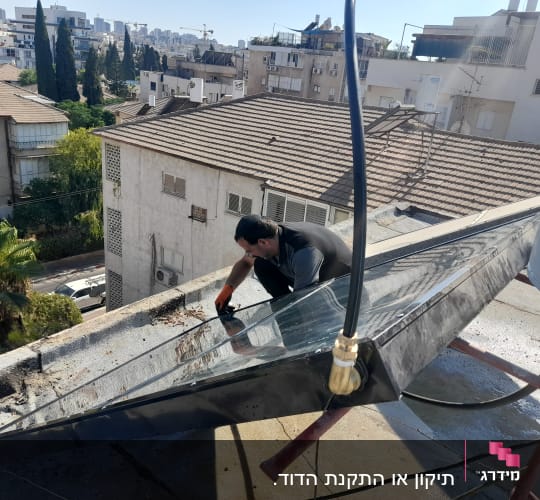 אדם עובד על דוד שמש על גג בניין